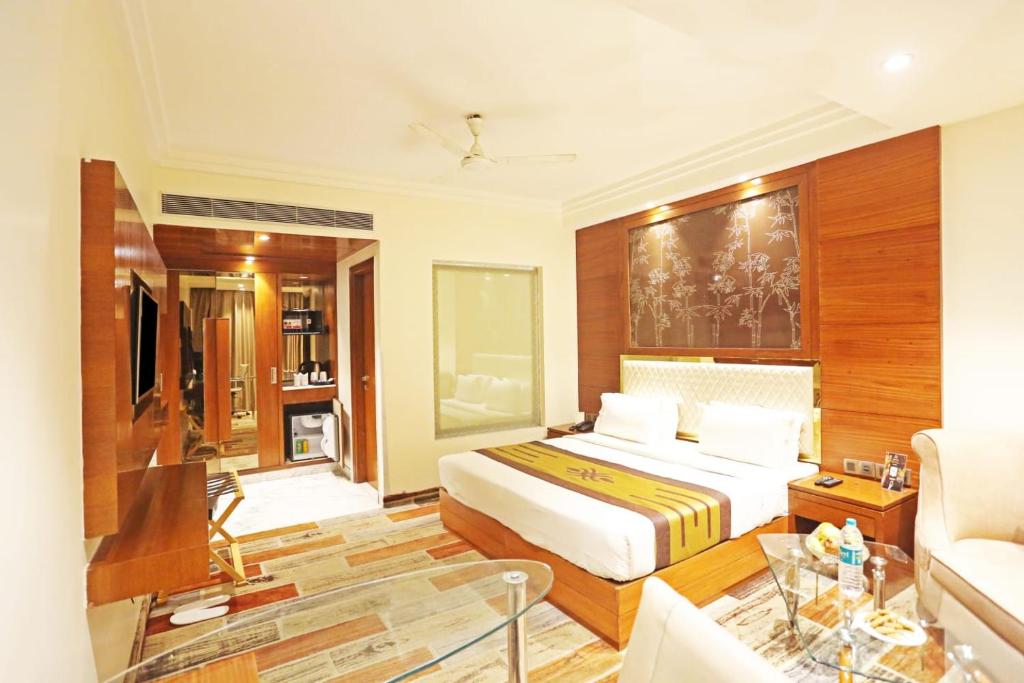 Hotel Aerotech Near Delhi Airport في نيودلهي: غرفة نوم مع سرير وغرفة معيشة