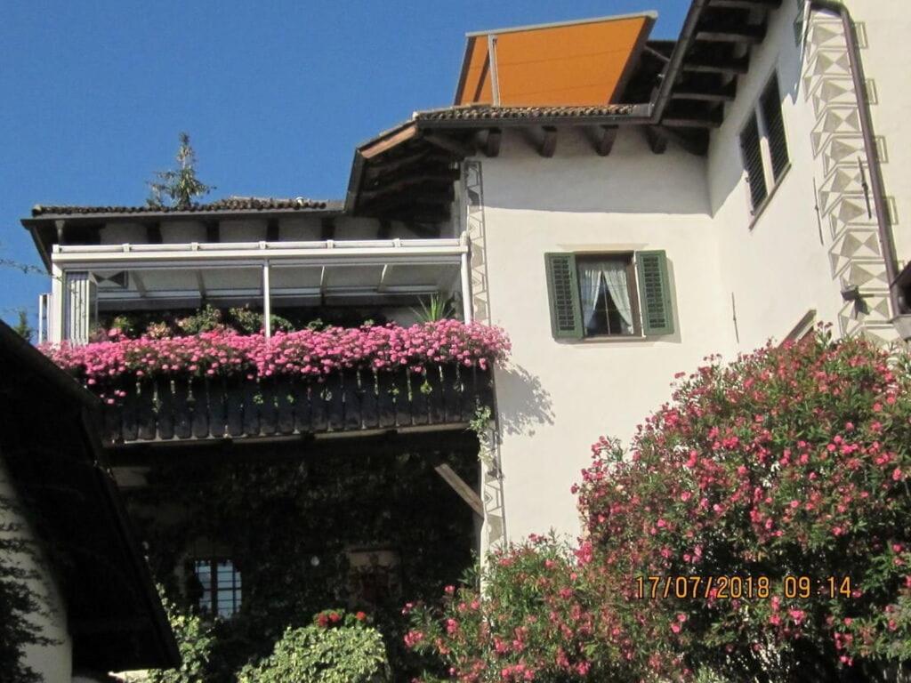 biały budynek z różowymi kwiatami na balkonie w obiekcie Landgoed Wendelstein w mieście Appiano sulla Strada del Vino