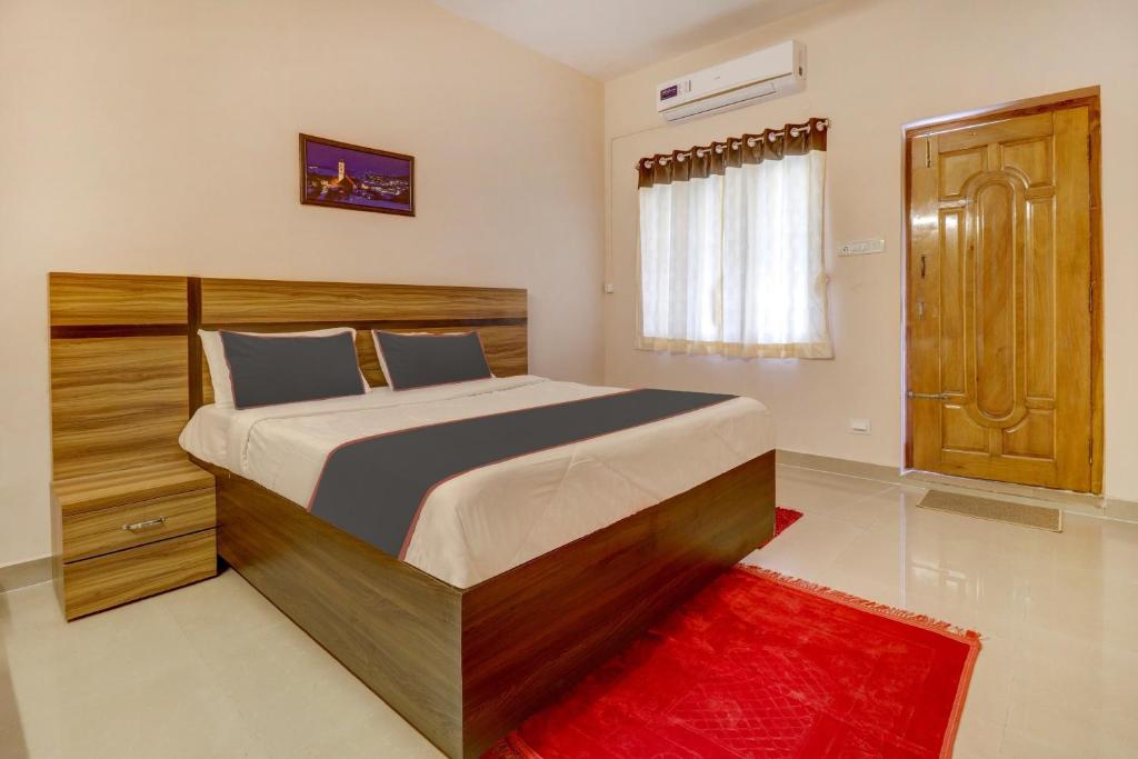 Super OYO V M Inn في تيروباتي: غرفة نوم بسرير وسجادة حمراء