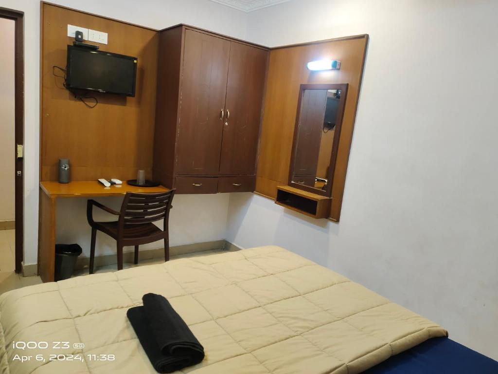 a bedroom with a bed and a table and a chair at Nest Inn in Puducherry