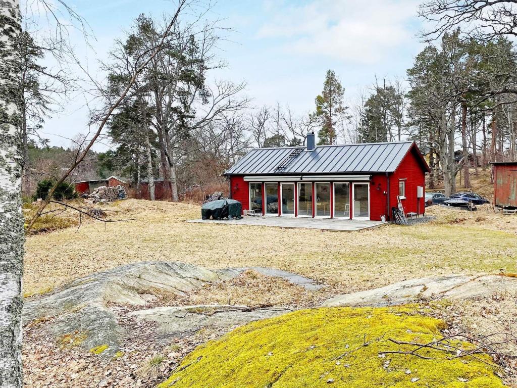 uma casa vermelha com um telhado preto num campo em Holiday home VAXHOLM II em Vaxholm