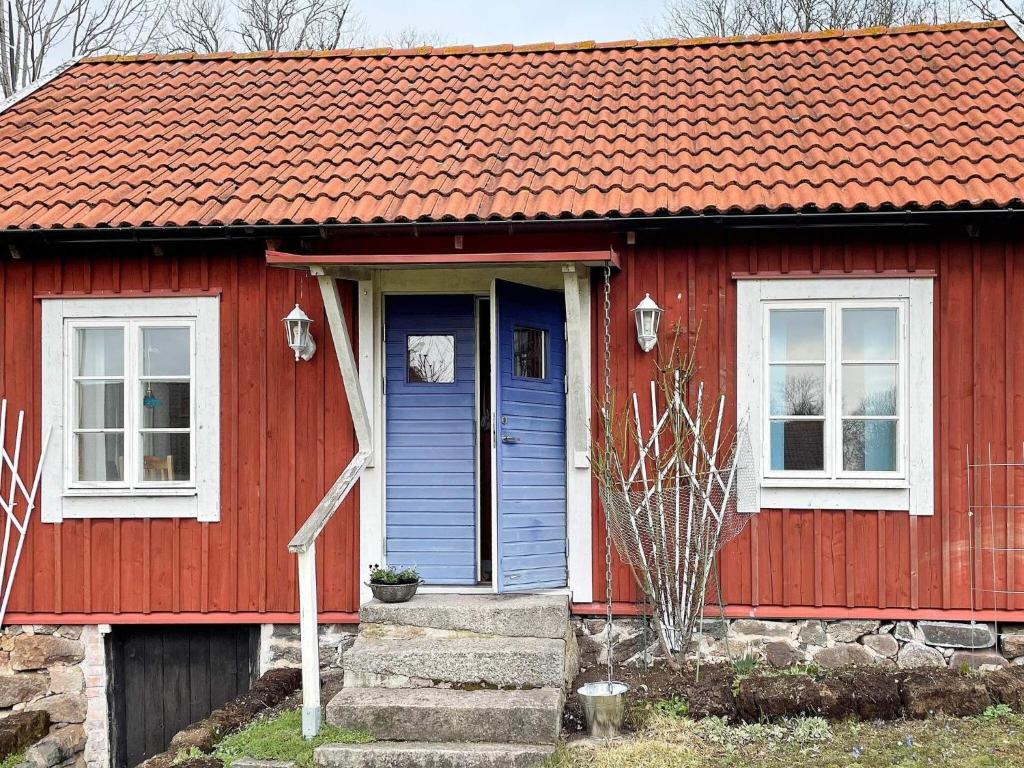 Holiday home Ronneby XV في رونيبي: منزل احمر بسقف برتقالي وباب ازرق