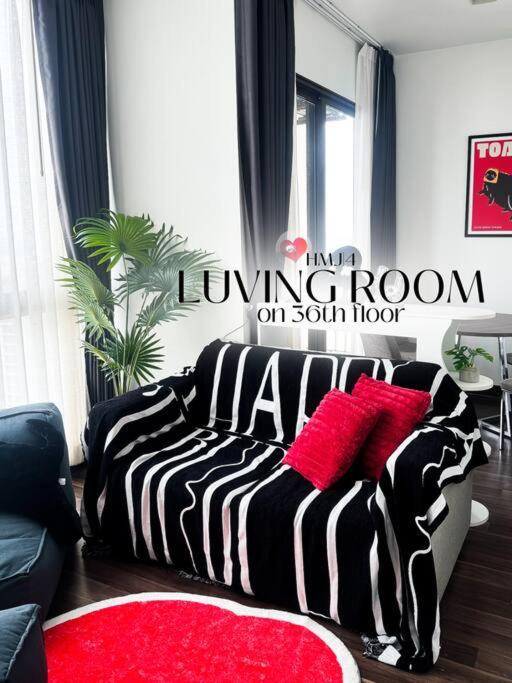 ein Wohnzimmer mit einem schwarzen und weißen Bett mit roten Kissen in der Unterkunft HMJ4 2BR stylish apartment on 36th floor KKC City center in Khon Kaen