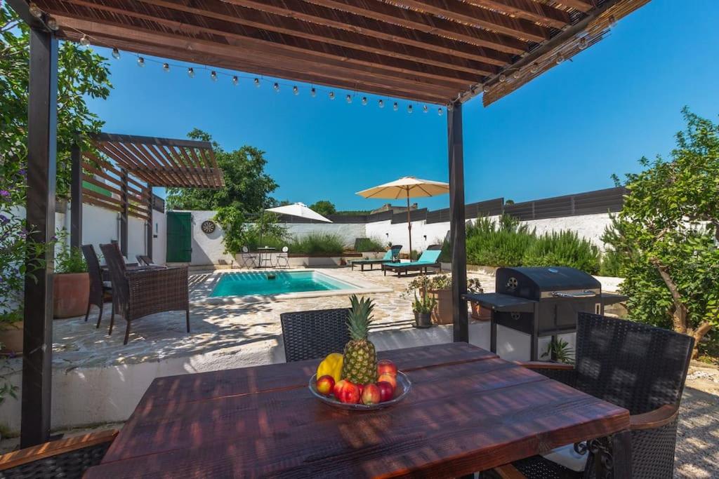 a wooden table with a bowl of fruit on a patio at Kuća za odmor Laurus s bazenom in Kukljica