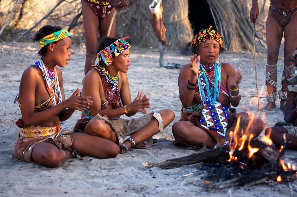 un grupo de personas sentadas alrededor de un fuego en Tsumkwe Country Lodge, en Tsumkwe