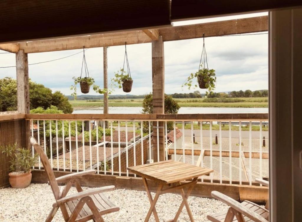 un patio con tavolo, sedie e vista sull'acqua di Maas Suites (Maastricht - Lanaken) a Lanaken