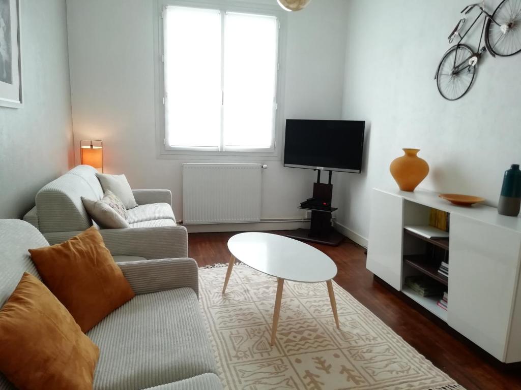 a living room with a couch and a table at La réserve à bonheurs in Les Sables-d'Olonne