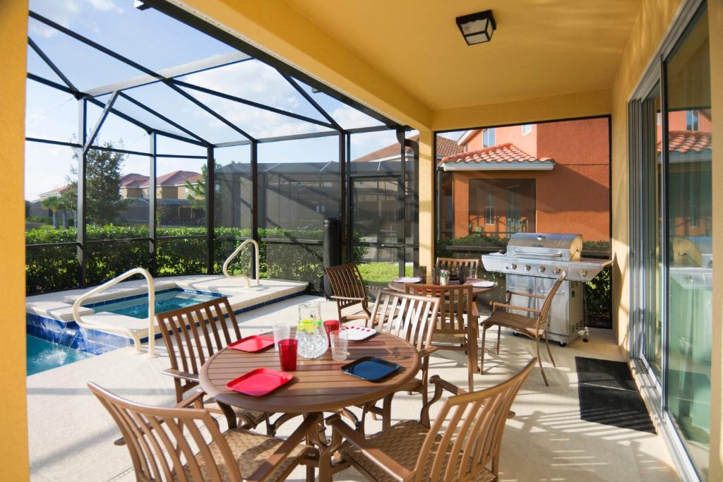 a patio with a table and chairs and a swimming pool at Solterra Resort 5 Bedroom Vacation Home with Pool 1604 in Davenport