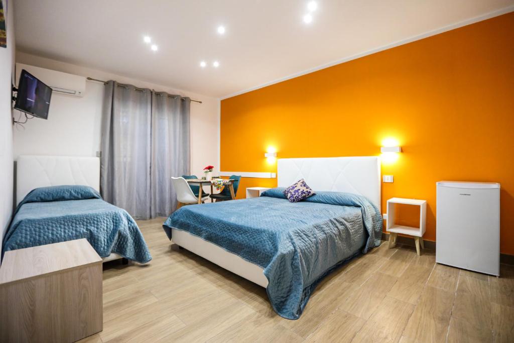 1 dormitorio con 2 camas y pared de color naranja en DUE CAPPUCCINI en Palermo