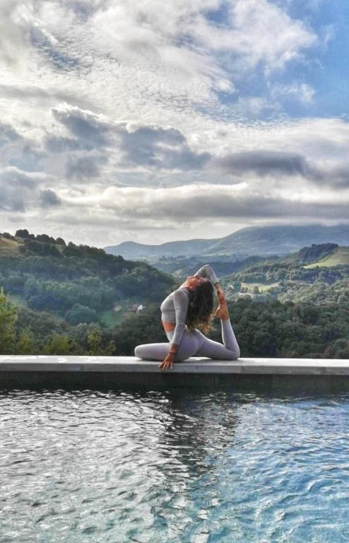 une femme assise sur une planche de surf à côté d'une masse d'eau dans l'établissement Studio Baïgura - Déconnexion au Pays basque, à Hasparren