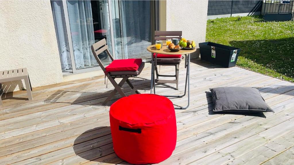 un pouf rouge assis sur une terrasse avec une table dans l'établissement La Coccinelle YourHostHelper, à Gujan-Mestras