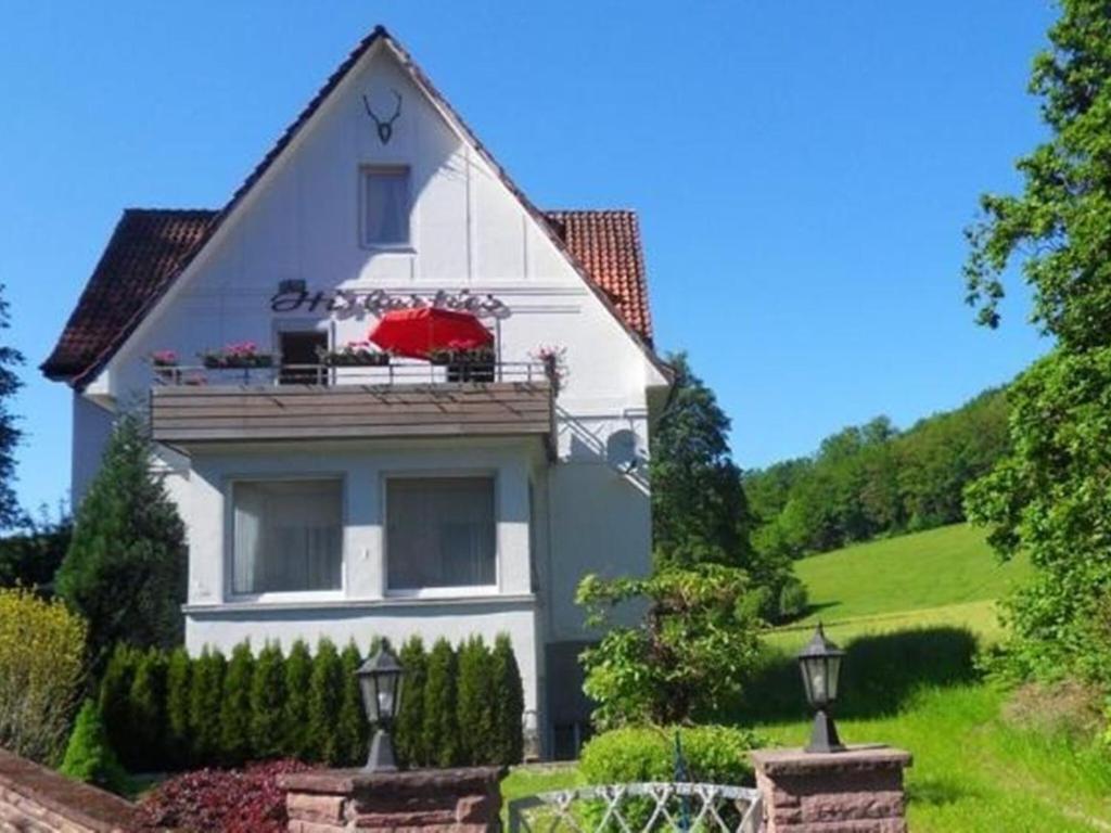 ein weißes Haus mit einem Balkon mit einem roten Regenschirm in der Unterkunft Spacious apartment in Weser Uplands with garden in Bad Pyrmont