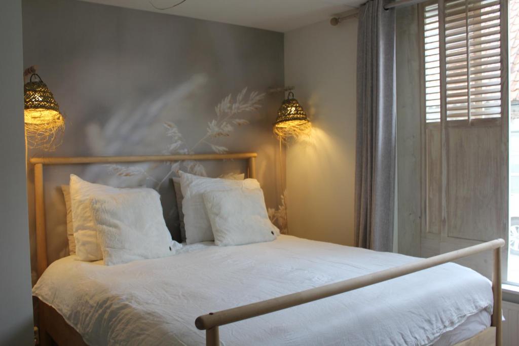 1 dormitorio con 1 cama con almohadas blancas y 2 luces en Casa By Sil's, en Colijnsplaat