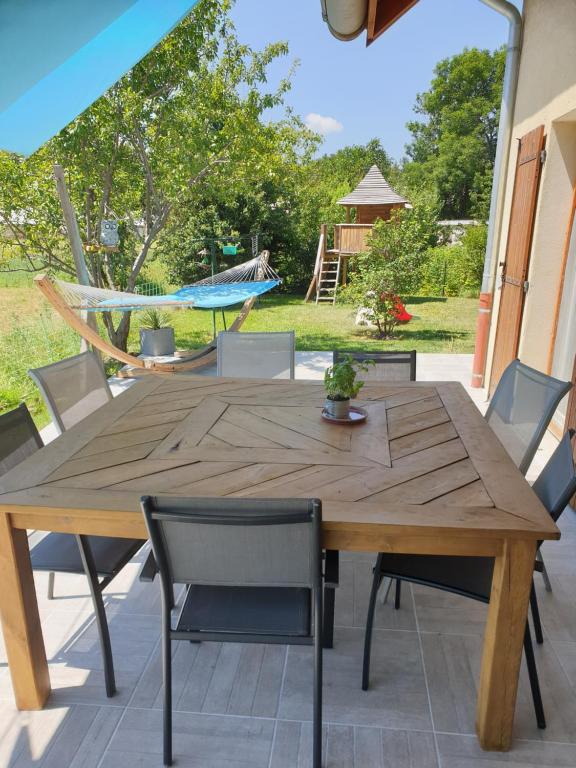 une table et des chaises en bois sur une terrasse avec un hamac dans l'établissement Maison entre lac et montagne, à Prunières