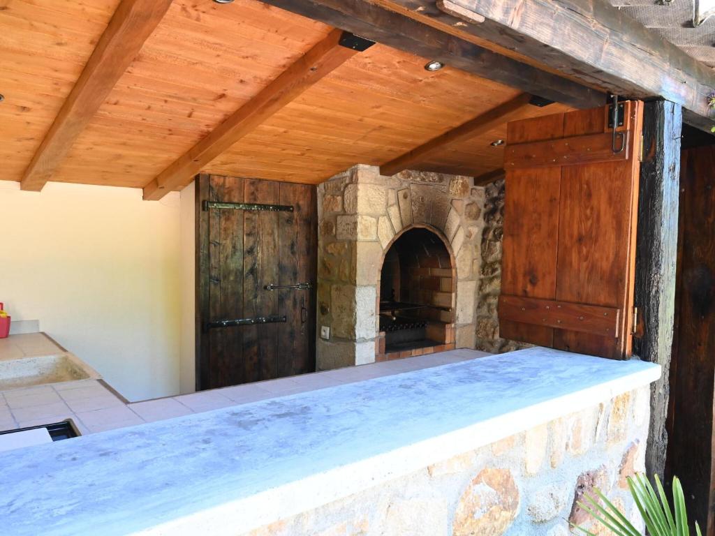 an outdoor kitchen with wooden ceilings and a stone wall at Restful Villa in Largenti re with Swimming Pool in Montréal