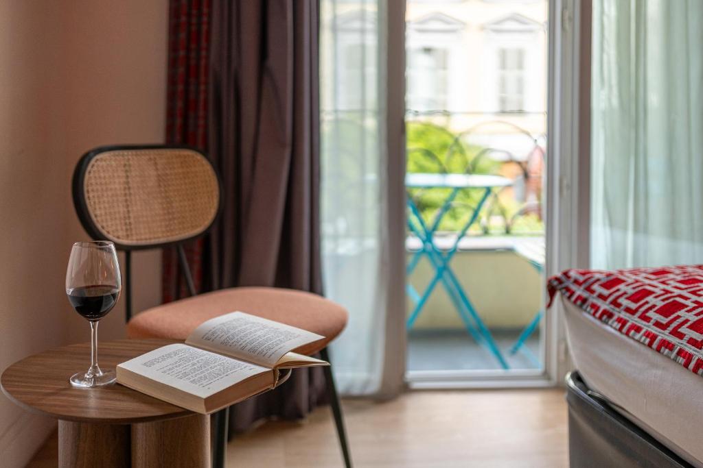 a bedroom with a glass of wine and a chair with a book at Hotel Boréal Nice in Nice