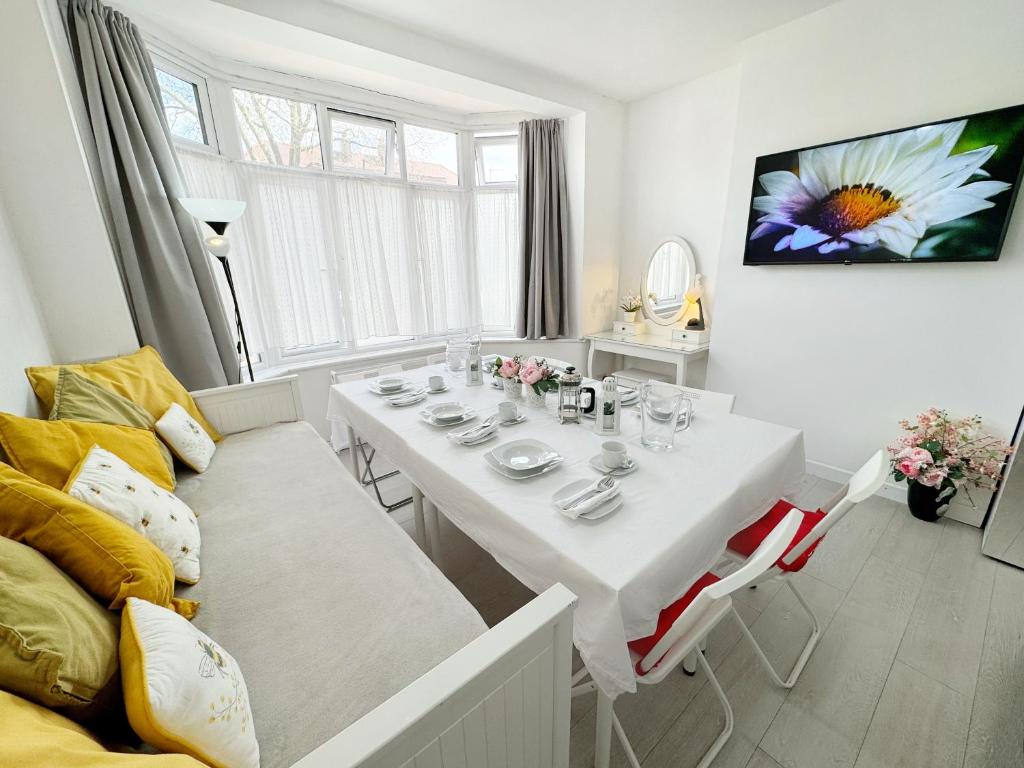 biała jadalnia z białym stołem i krzesłami w obiekcie Luxurious House near Excel- Air Conditioning, 9 Beds, 2 Baths, Garden, fast WiFi w Londynie