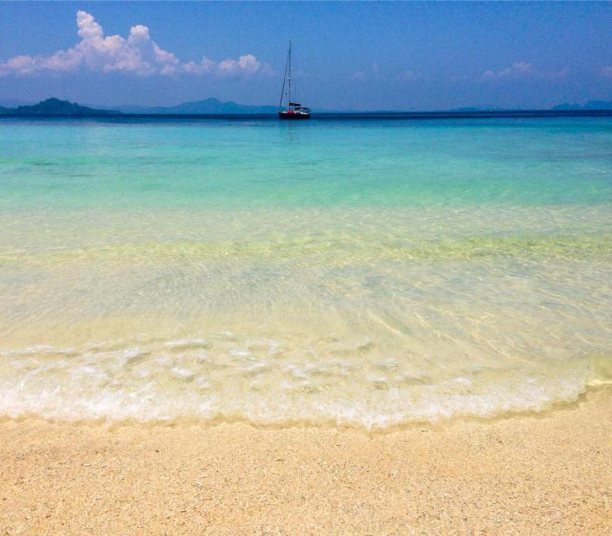 Kradan Beach Resort في كوه كرادان: شاطئ مع قارب شراعي في الماء
