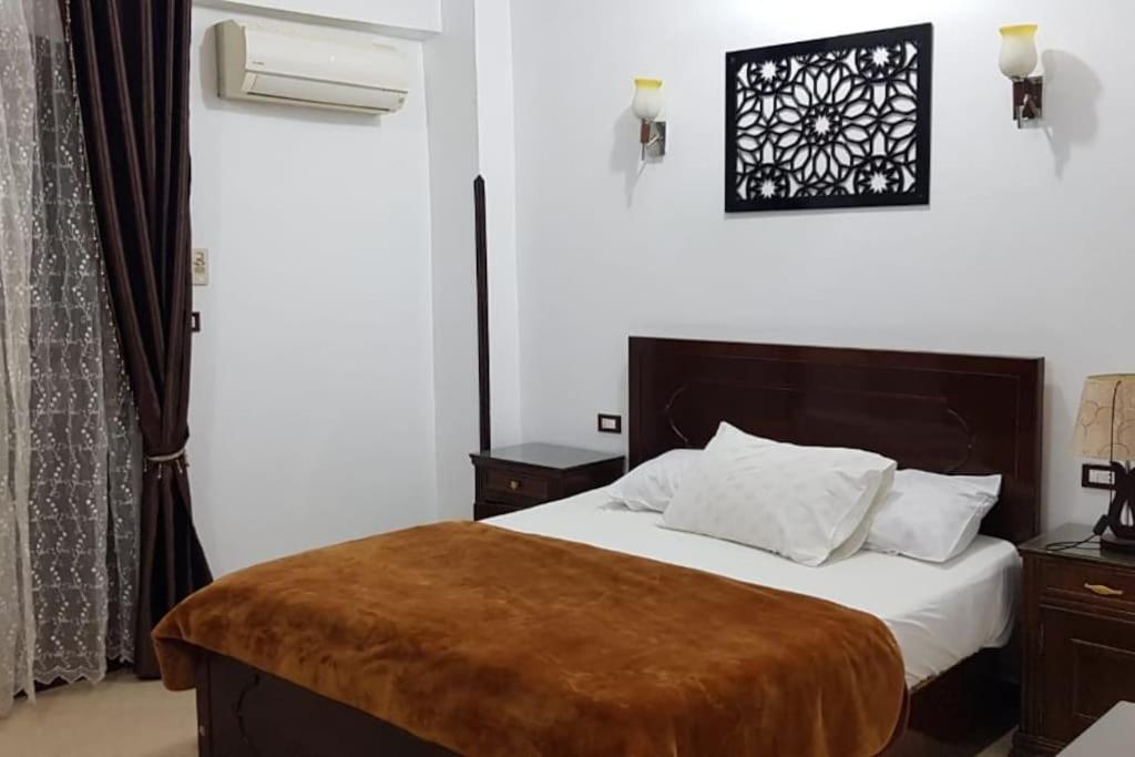 um quarto com uma cama com um cobertor castanho em Elminaa Residents 2 em Luxor