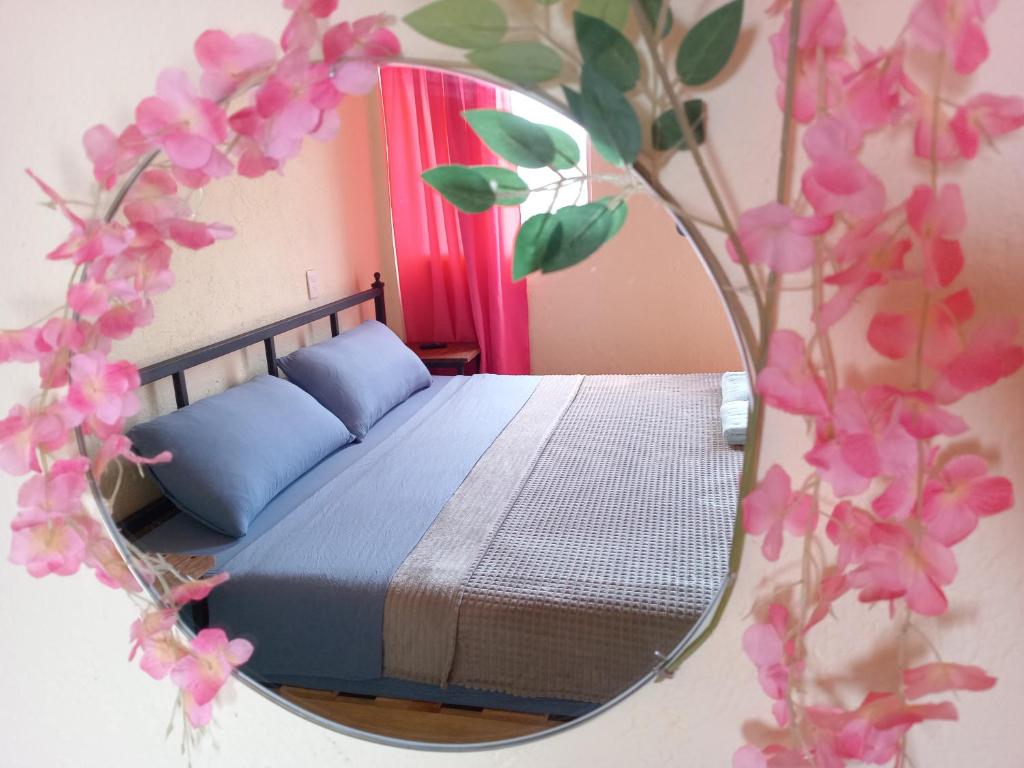 um quarto com uma cama e um espelho com flores cor-de-rosa em terraza netzahualcoyotl em Tepoztlán