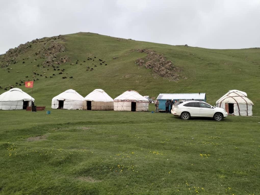 une voiture garée dans un champ à côté de certaines tentes dans l'établissement Kanat Yurt Camp, à Shamaldy-Say