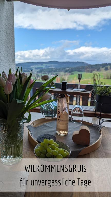 una mesa con un plato de uvas y una botella en Ferienwohnung Bergzeit mit Pool und Sauna en Missen-Wilhams