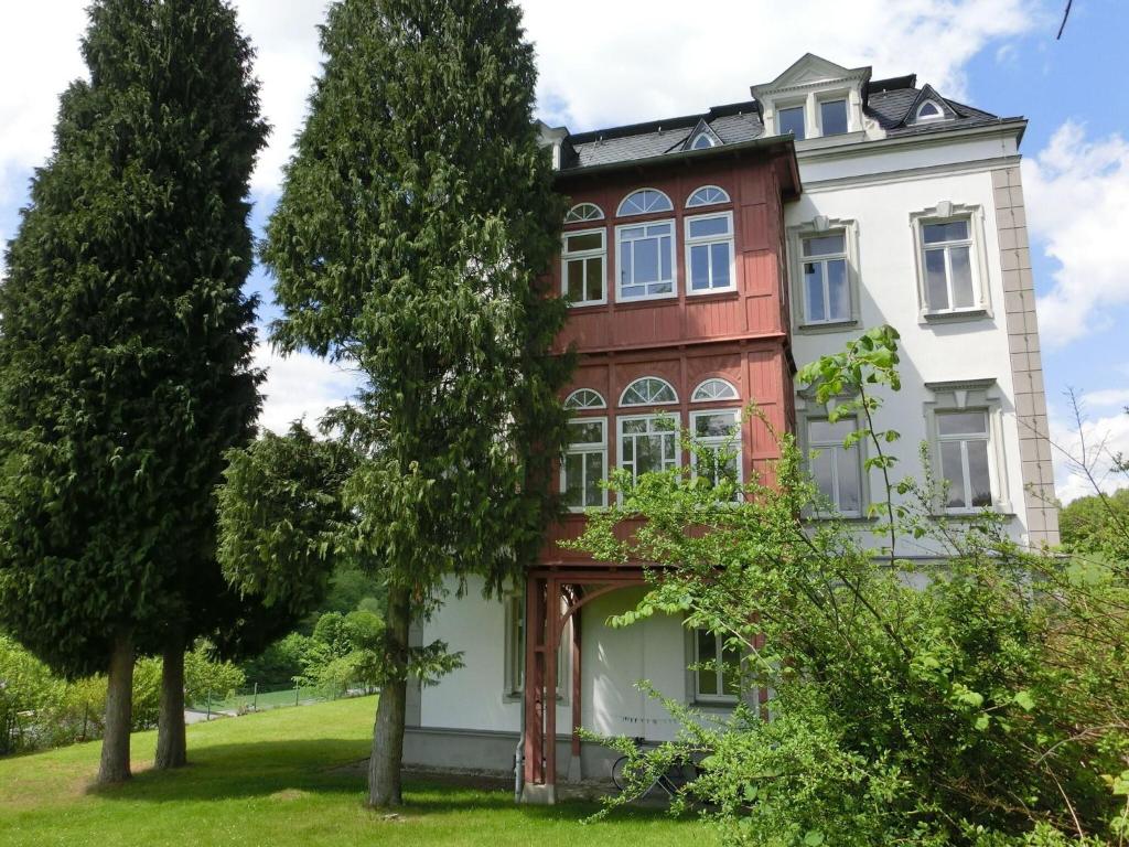 ein altes Haus mit Bäumen davor in der Unterkunft Alluring Villa in Grunhainichen Borstendorf with Garden in Leubsdorf