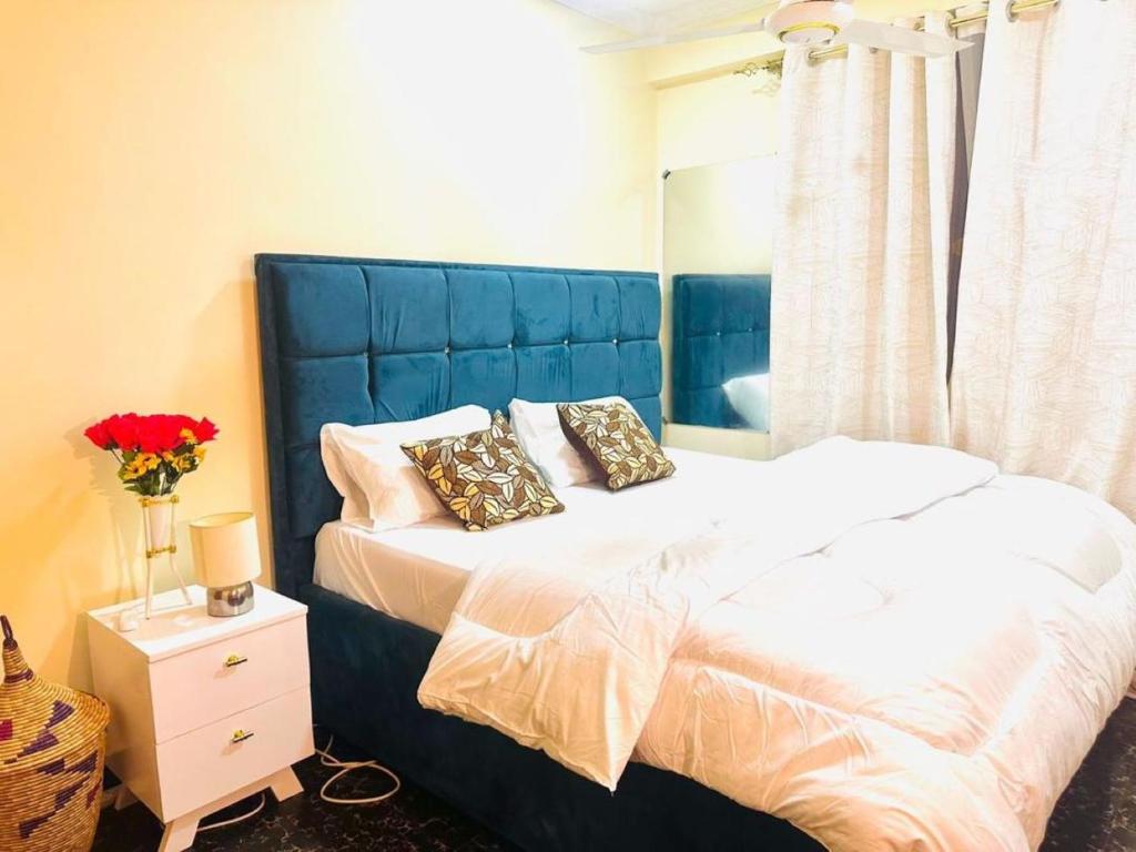 een slaapkamer met een bed met een blauw hoofdeinde en kussens bij The central Heartbeat Haven Intercity in Dar es Salaam