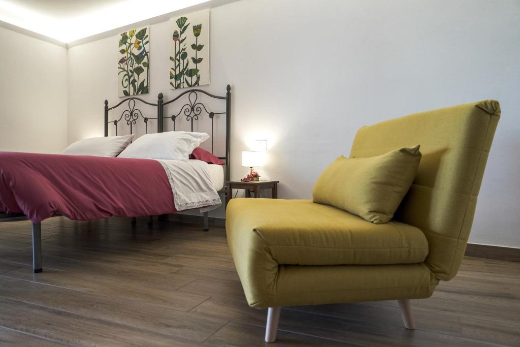 a bedroom with a bed and a yellow chair at La Casa del Fabbro in Troina
