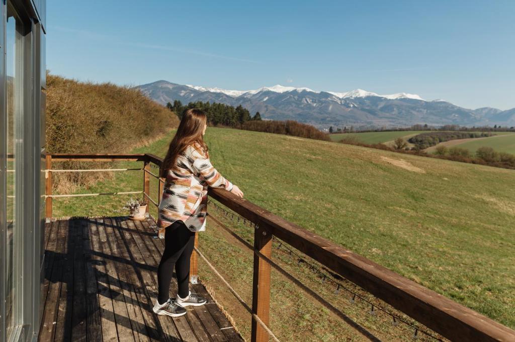 a woman standing on a balcony looking at the mountains at Sidehill - zážitkové ubytovanie v prírode in Martin