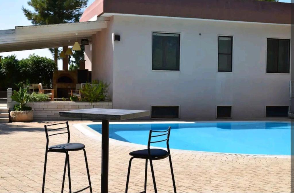 - une table et deux chaises à côté de la piscine dans l'établissement Villa Mialma, à Monopoli