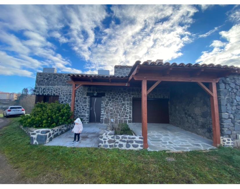 une femme debout devant une maison en pierre dans l'établissement Gîte chez Maddy, à Chilhac