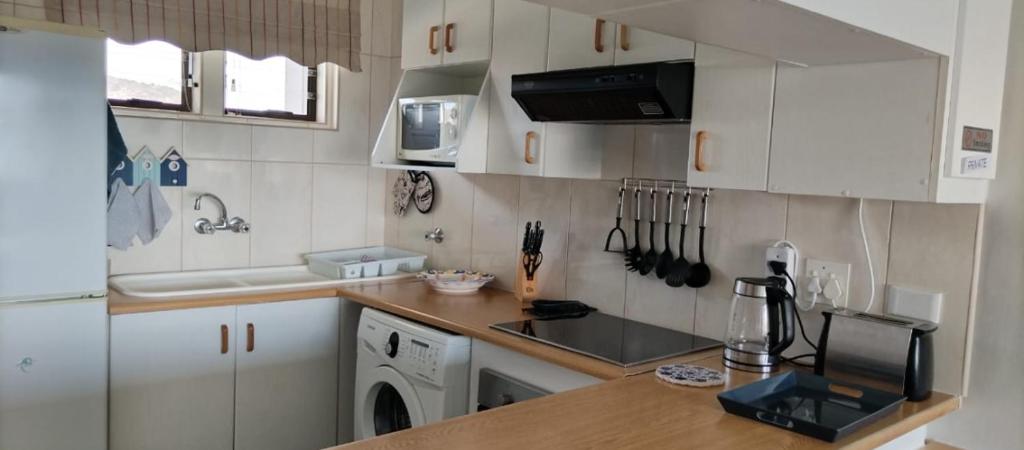 a kitchen with white cabinets and a counter top at De Valle 37 in Mossel Bay