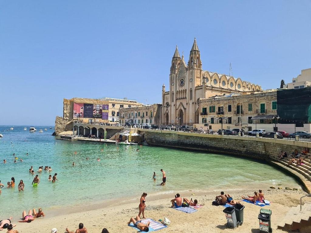 un grupo de personas en el agua en una playa en Brand New St. Julian's Luxury Apartment - Wish Malta en St Julian's