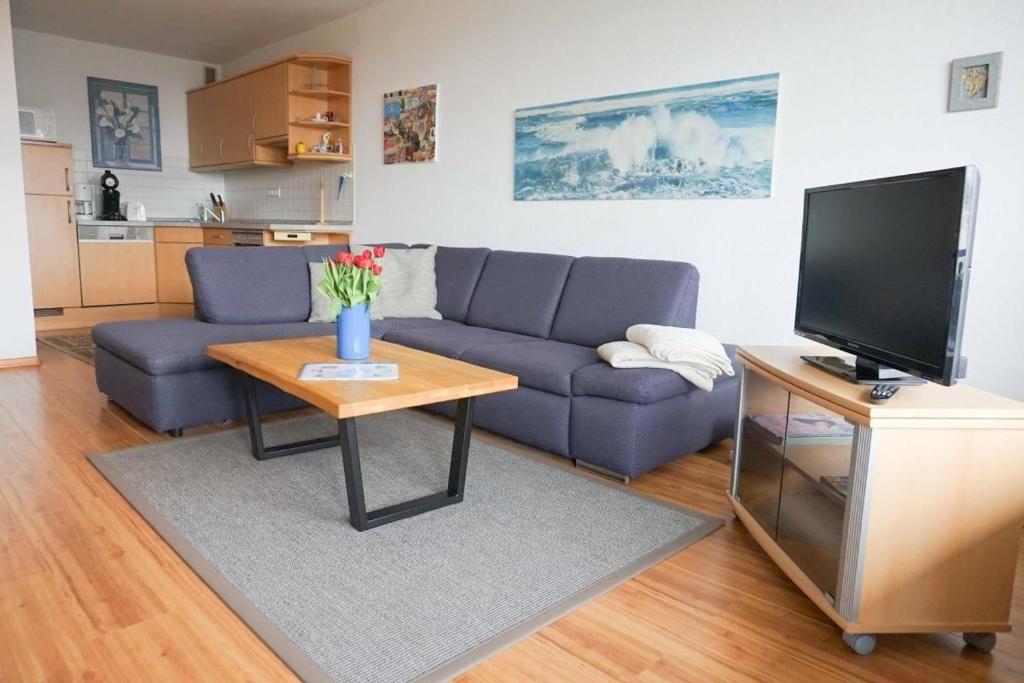ein Wohnzimmer mit einem Sofa und einem Tisch mit einem TV in der Unterkunft Ferienwohnung Seetempel Wohnung Nr.29 in Scharbeutz