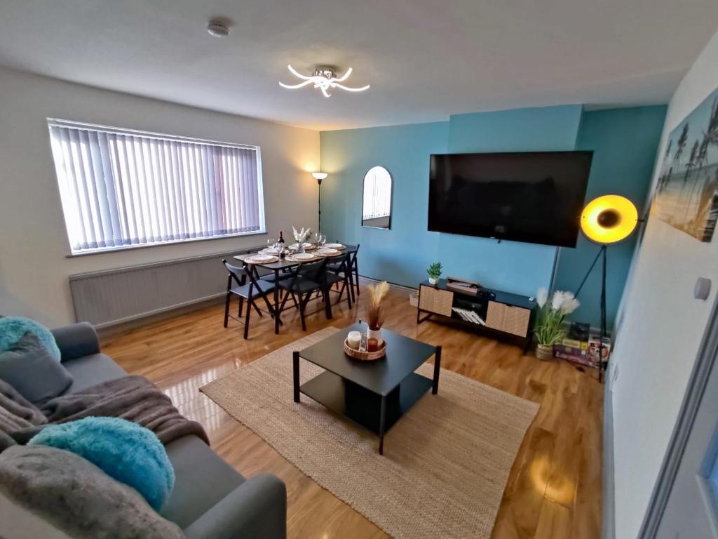 a living room with a couch and a table at Leeds Beach House, Free Parkings, Sandy private backyard, 70 Inch Smart Tv, X box, Large gardens Included in Killingbeck