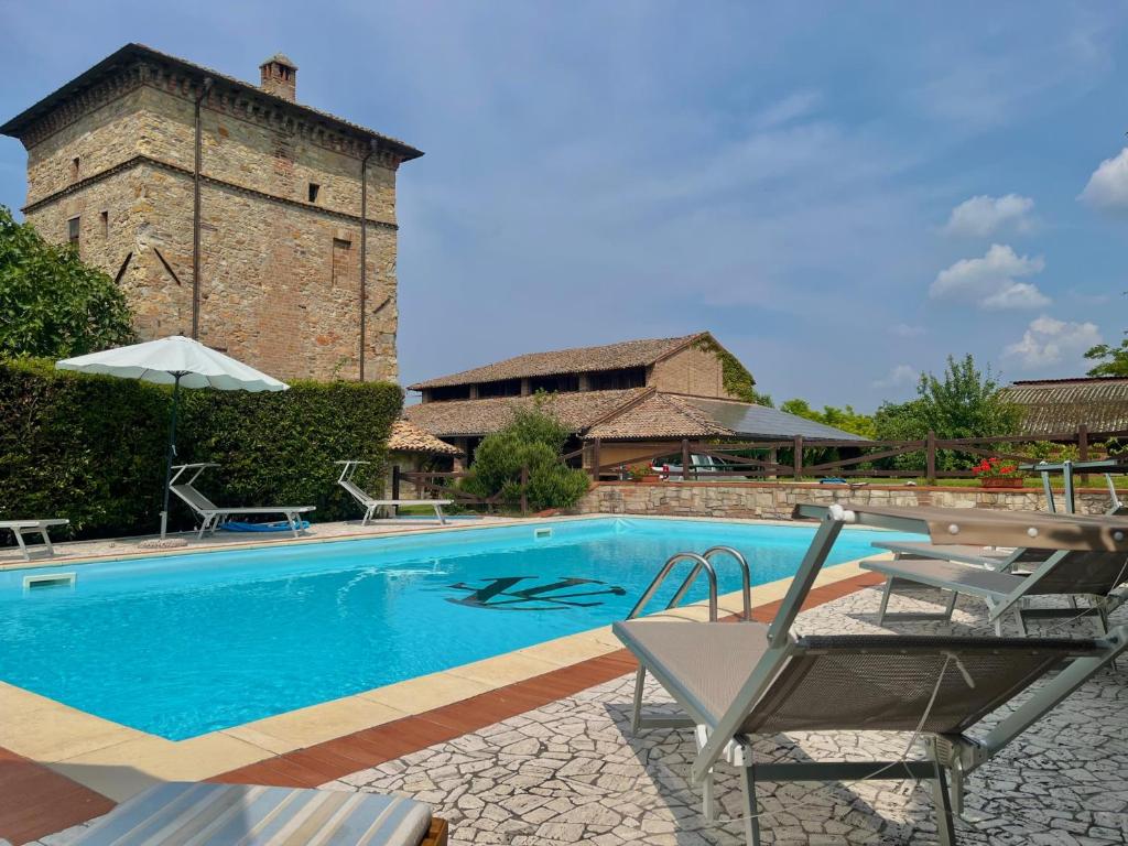 a swimming pool with two chairs and a building at Antica Torre in Salsomaggiore Terme