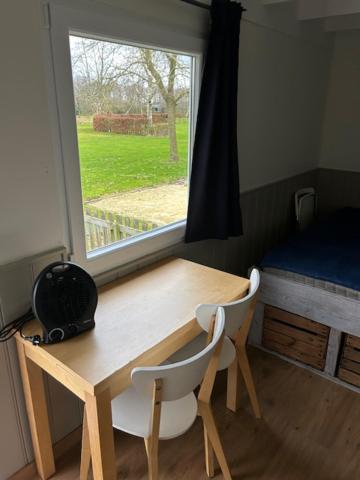 una mesa de madera con 2 sillas y una ventana en Pieterwagen, en Sleen