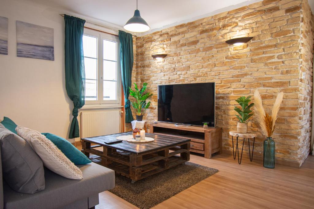 een woonkamer met een tv en een bakstenen muur bij La Roche dorée I Grand appartement centre ville in Brest