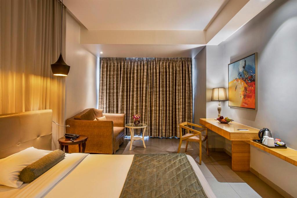 a hotel room with a bed and a desk at Hotel Satkar Grande in Thane