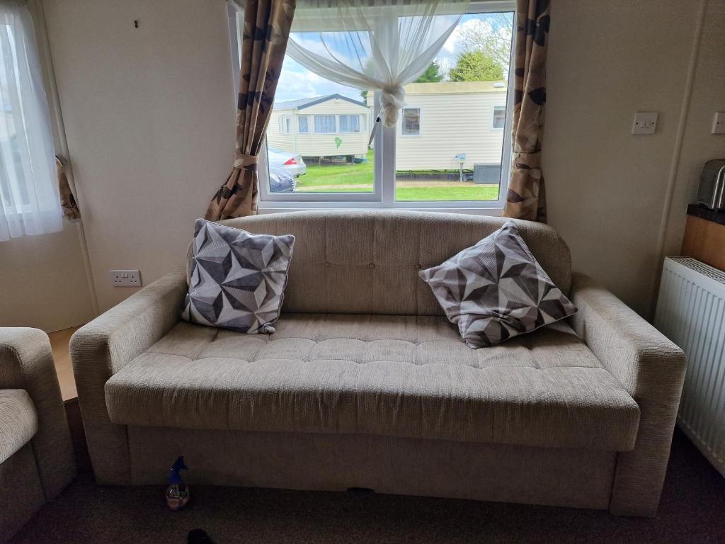 a couch with two pillows sitting in front of a window at Plot 203 paris in Rhyl