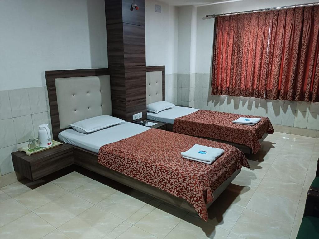 a bedroom with two beds and a window at Hotel Orchid in Guwahati