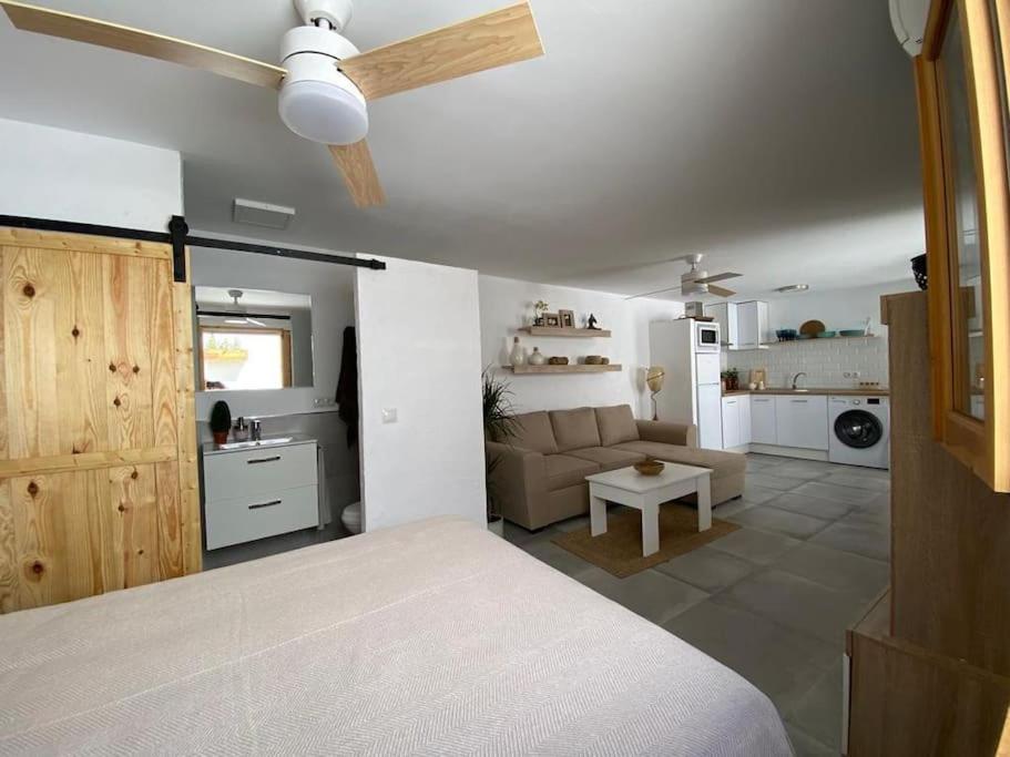 um quarto com uma ventoinha de tecto e uma sala de estar em La casita de la abuela María em Almeria