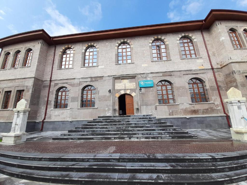 Un grand bâtiment en pierre avec des escaliers se trouve juste devant. dans l'établissement VE HOTELS KAPADOKYA, à Nevşehir