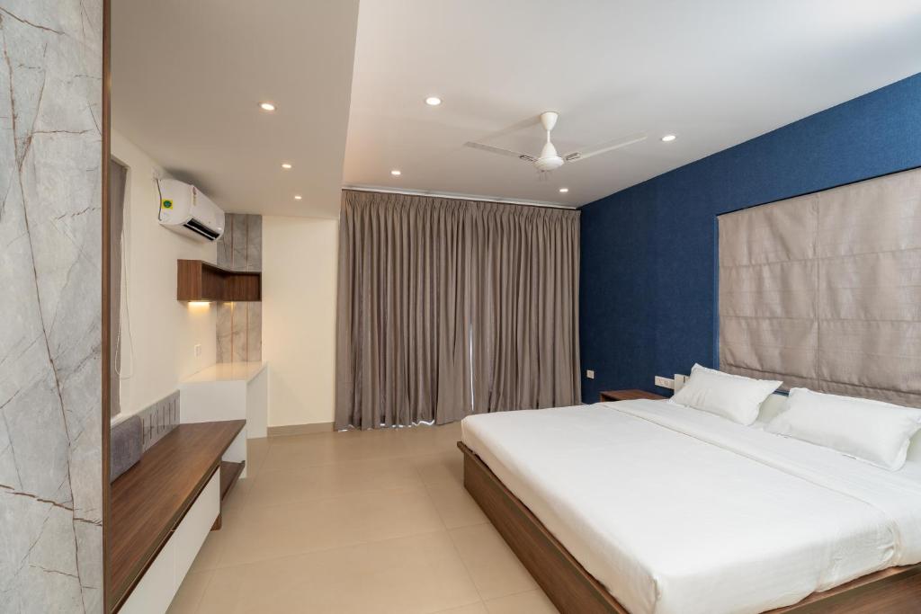 een slaapkamer met een groot bed en een blauwe muur bij Lumiere Premium Apartments in Trivandrum