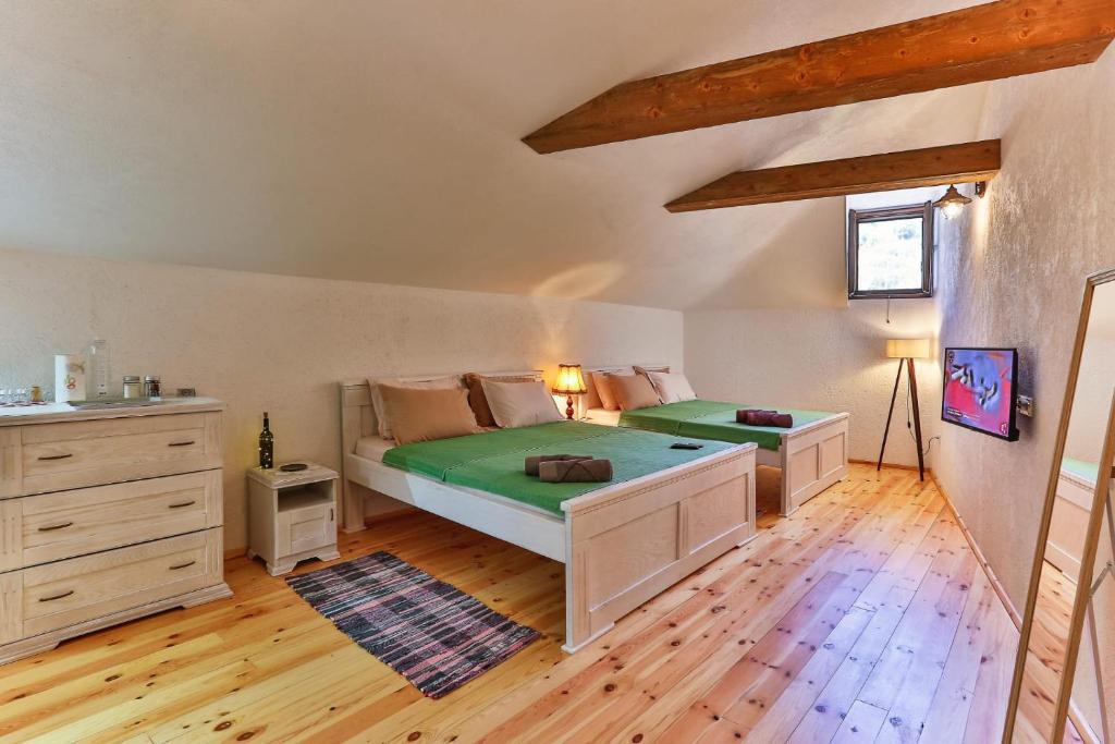 Schlafzimmer mit einem Bett mit grüner Bettwäsche und Holzboden in der Unterkunft Iguana House in Stari Bar