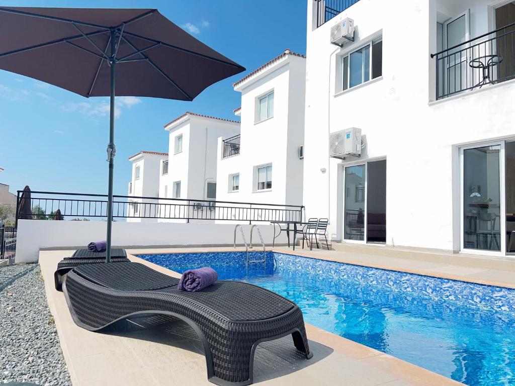 a villa with a swimming pool and an umbrella at White Mountain Pool Villas in Paphos City
