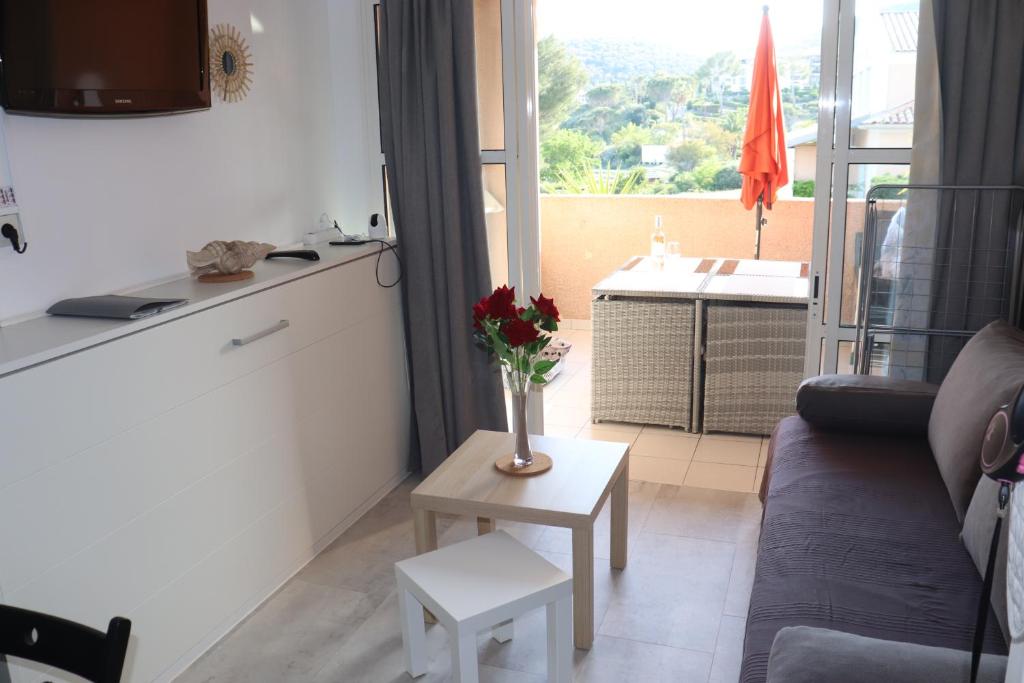 un salon avec un canapé et une table avec des fleurs dans l'établissement T2 climatisé wifi piscines parking, à Saint-Raphaël
