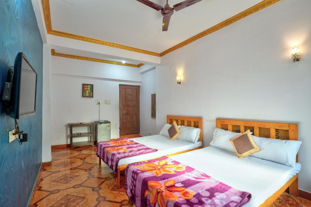 Om Sai Guest House في كالانغيُت: غرفة نوم بسريرين وتلفزيون بشاشة مسطحة