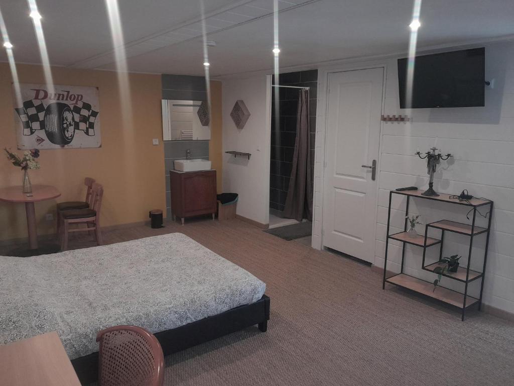 Schlafzimmer mit einem Bett, einem Tisch und einer Tür in der Unterkunft chambre sérénité in Condé-sur-Noireau